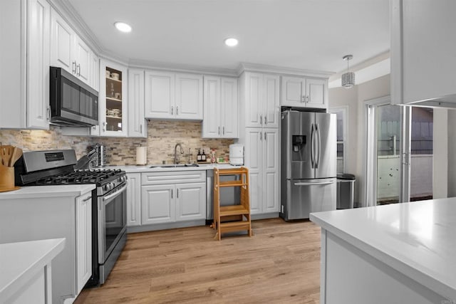 kitchen with white cabinets, stainless steel appliances, a sink, and light countertops