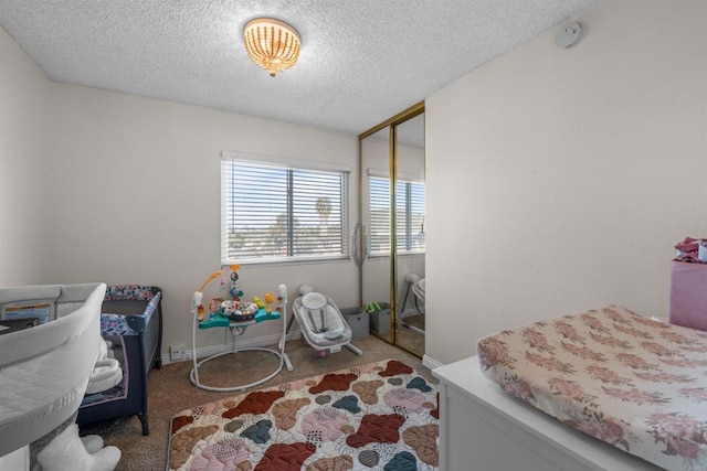 carpeted bedroom with a textured ceiling, a closet, and baseboards