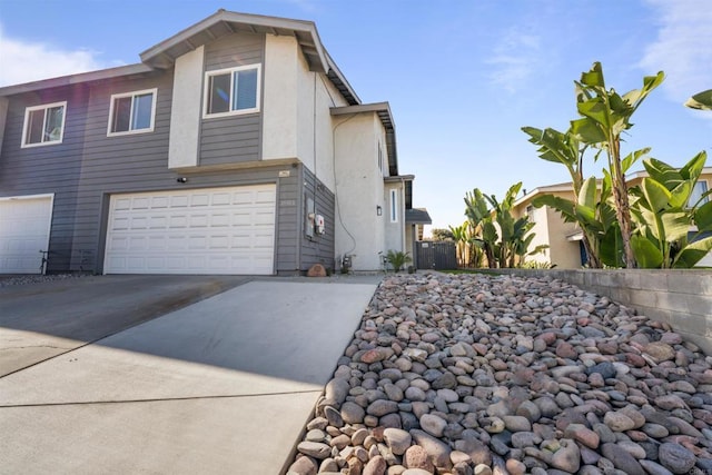 view of side of home featuring driveway, an attached garage, and fence