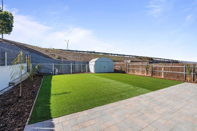 view of yard featuring a storage shed, a fenced backyard, a patio, and an outbuilding