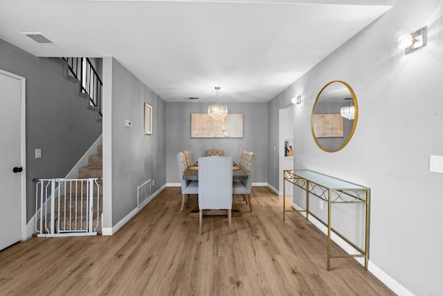 dining area featuring baseboards, stairs, visible vents, and wood finished floors