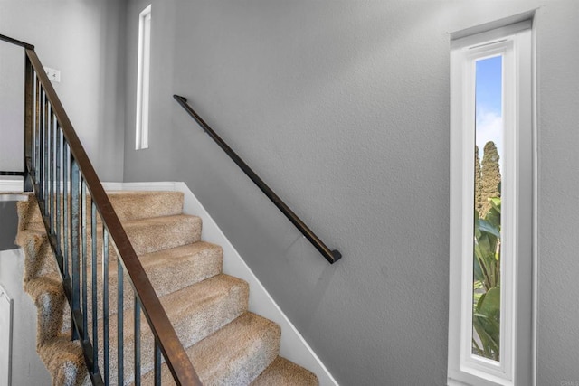 stairs featuring a textured wall and baseboards