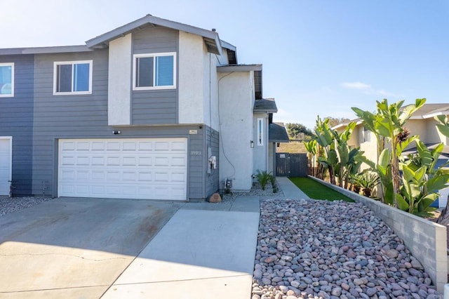 view of front facade featuring concrete driveway, an attached garage, and fence