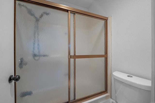 bathroom featuring toilet and a shower with shower door