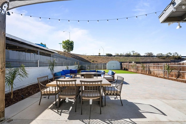 view of patio featuring an outbuilding, a shed, outdoor dining space, and a fenced backyard