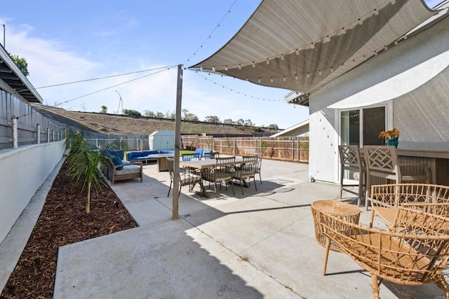 view of patio / terrace with an outbuilding, a fenced backyard, outdoor lounge area, a shed, and outdoor dining space