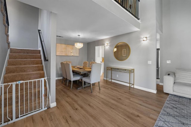 dining room featuring stairs, a chandelier, wood finished floors, and baseboards