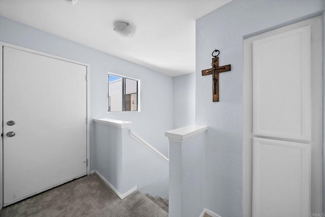 corridor featuring carpet floors, baseboards, and an upstairs landing