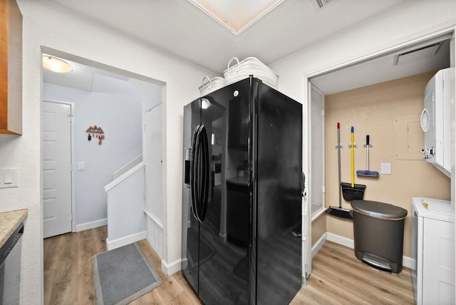 kitchen featuring washer / clothes dryer, baseboards, light countertops, light wood-type flooring, and black refrigerator with ice dispenser