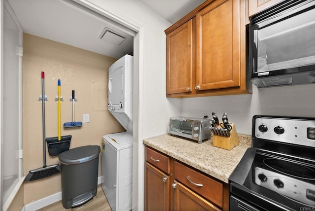 washroom with laundry area, a toaster, visible vents, stacked washer / drying machine, and light wood-style floors