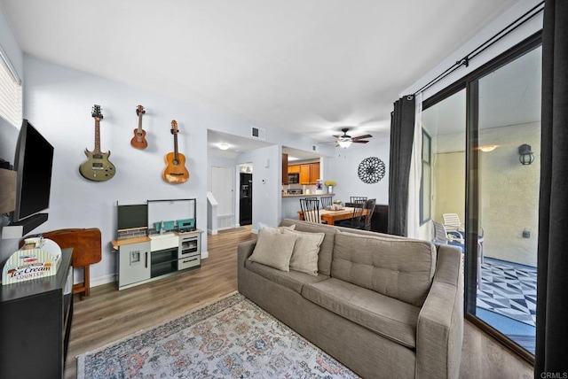 living area with visible vents, ceiling fan, baseboards, and wood finished floors