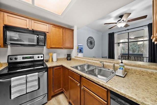 kitchen featuring brown cabinets, light countertops, stainless steel range with electric cooktop, black microwave, and a sink