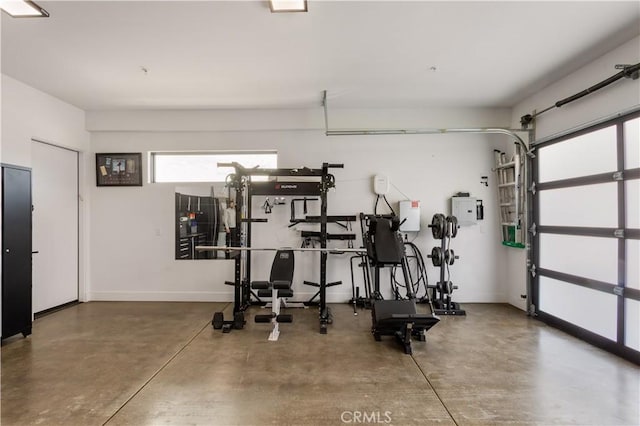 exercise area featuring a garage and baseboards