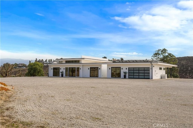 view of front of house featuring stucco siding, a mountain view, a garage, cooling unit, and driveway