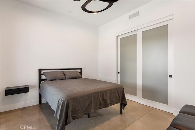 bedroom featuring a closet, visible vents, concrete floors, and baseboards