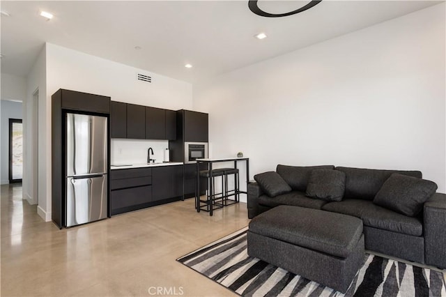 living area with concrete flooring, recessed lighting, and visible vents