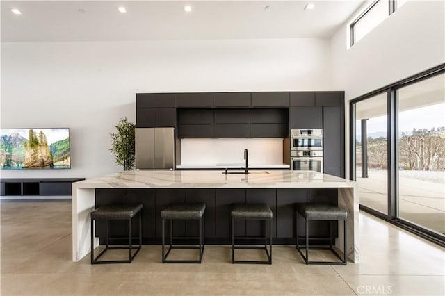 kitchen featuring stainless steel appliances, modern cabinets, a sink, and a kitchen breakfast bar