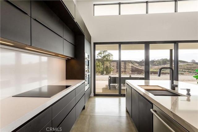 kitchen with black electric stovetop, light countertops, finished concrete floors, a sink, and dishwasher