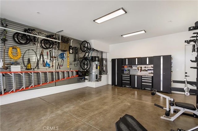 garage featuring baseboards, heat pump water heater, bike storage, and a workshop area