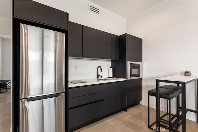 kitchen with light countertops, dark cabinetry, modern cabinets, and freestanding refrigerator