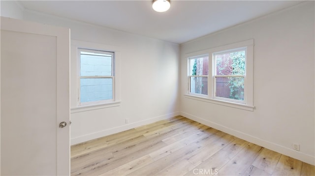 spare room with baseboards and light wood finished floors