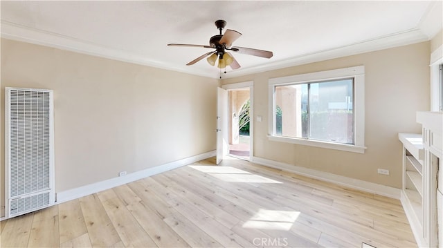 spare room featuring ceiling fan, wood finished floors, baseboards, a heating unit, and crown molding