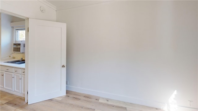 interior space with baseboards, wood finished floors, crown molding, cooling unit, and a sink