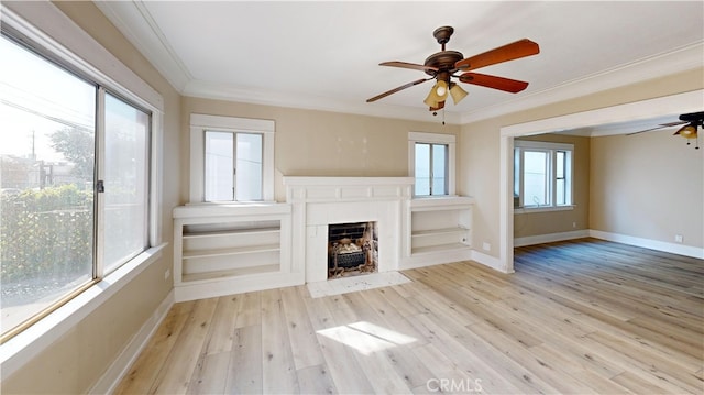 unfurnished living room with a wealth of natural light, ceiling fan, ornamental molding, and wood finished floors