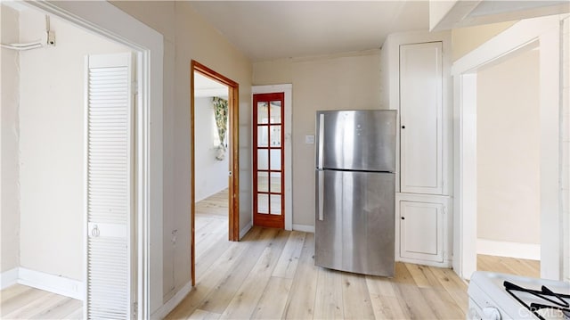 kitchen with light wood finished floors, baseboards, and freestanding refrigerator