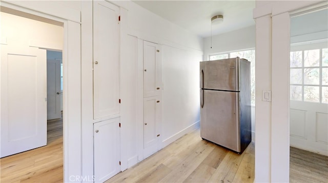 kitchen with light wood-type flooring, plenty of natural light, and freestanding refrigerator