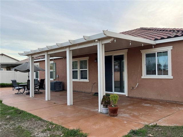 rear view of house featuring a patio, a tiled roof, fence, and stucco siding