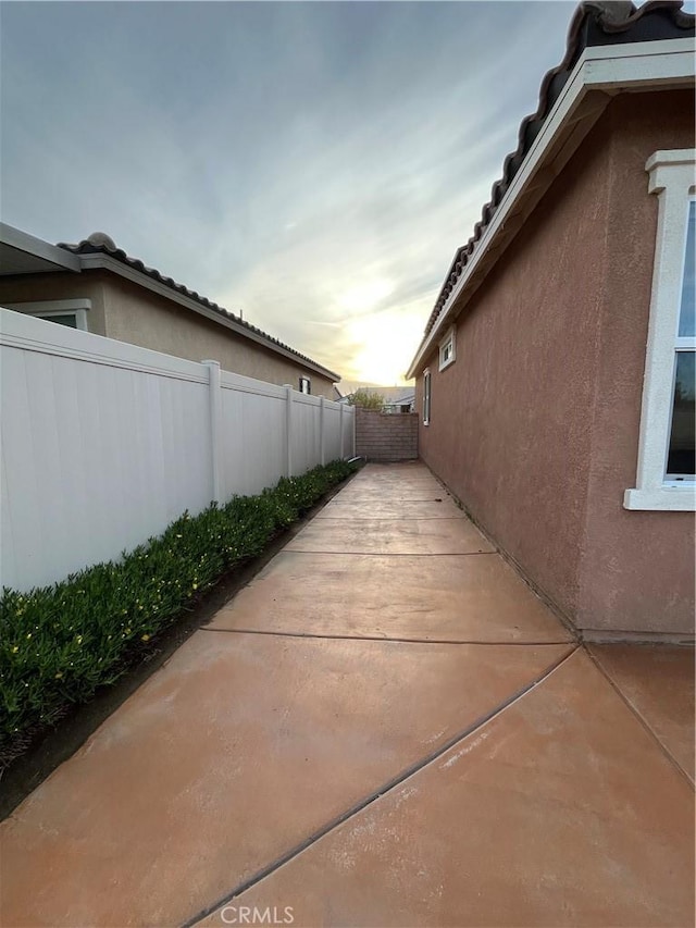 view of side of home with stucco siding, a patio, and a fenced backyard