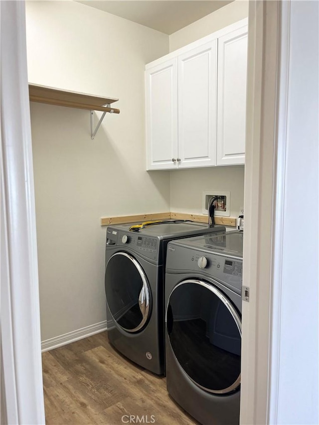 laundry area with cabinet space, washer and dryer, baseboards, and wood finished floors