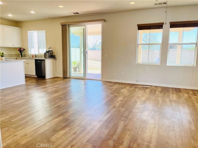 interior space featuring visible vents, dishwasher, wood finished floors, and white cabinets