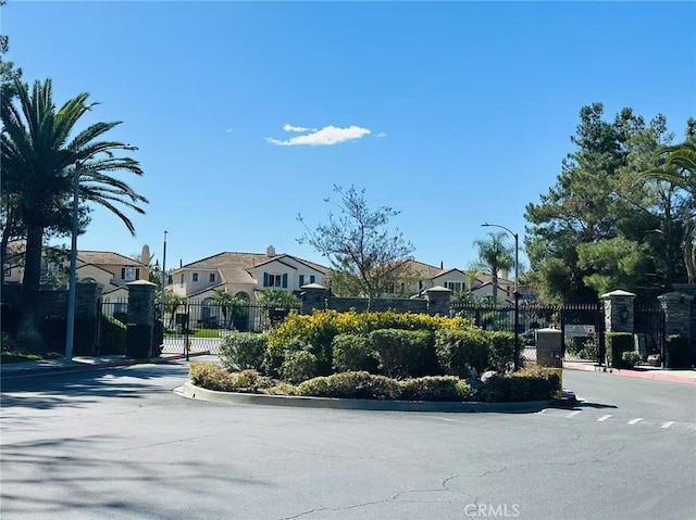 view of street with street lighting, a gate, a gated entry, a residential view, and curbs