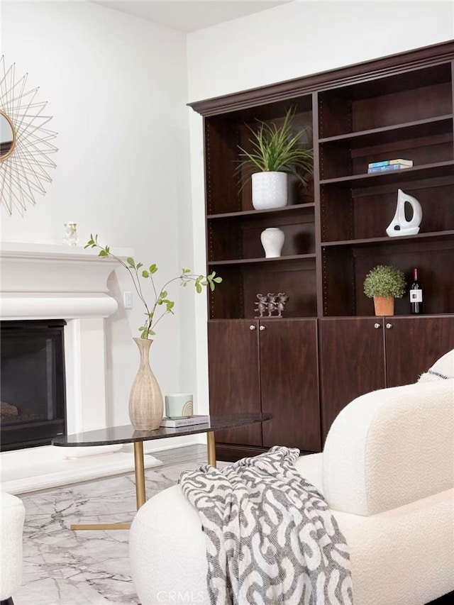 sitting room with a glass covered fireplace and marble finish floor