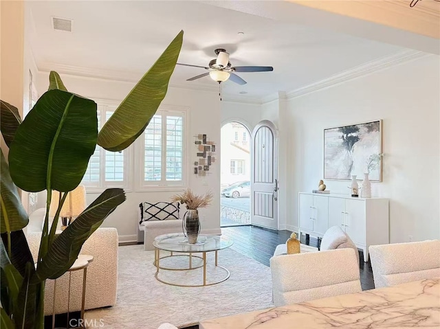 living area featuring baseboards, visible vents, crown molding, and wood finished floors