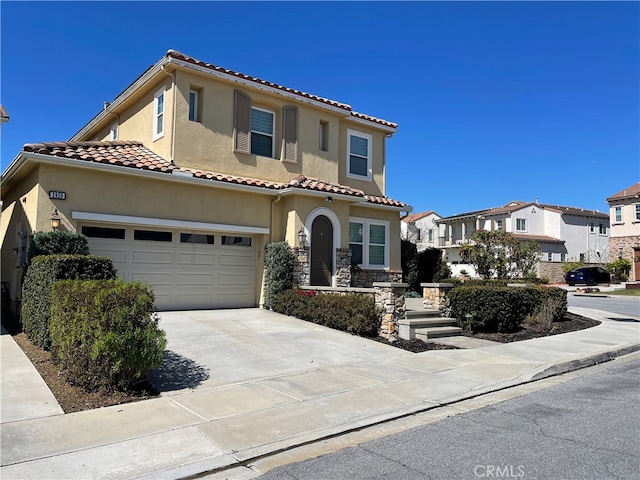 mediterranean / spanish home with concrete driveway, stone siding, a tile roof, a residential view, and stucco siding