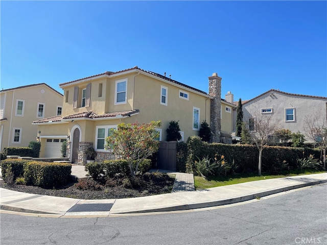 mediterranean / spanish house with a garage, stone siding, a tile roof, and stucco siding