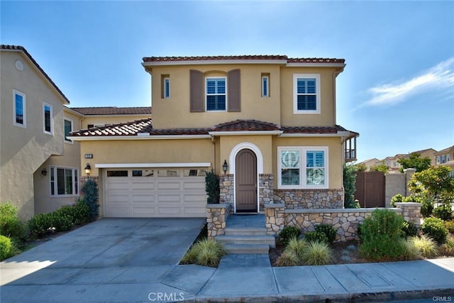 mediterranean / spanish home featuring a garage, fence, driveway, a tiled roof, and stucco siding