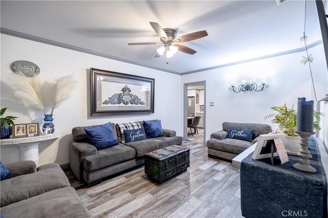 living room with ornamental molding, a ceiling fan, and light wood-style floors