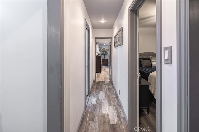 corridor with baseboards and wood finished floors