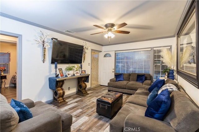 living room with baseboards, visible vents, ceiling fan, wood finished floors, and crown molding