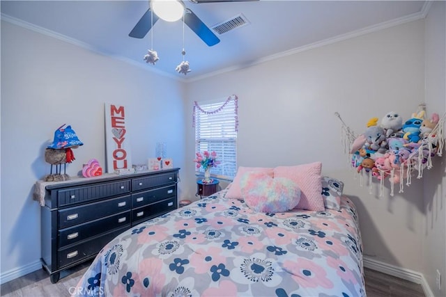 bedroom with crown molding, visible vents, a ceiling fan, wood finished floors, and baseboards