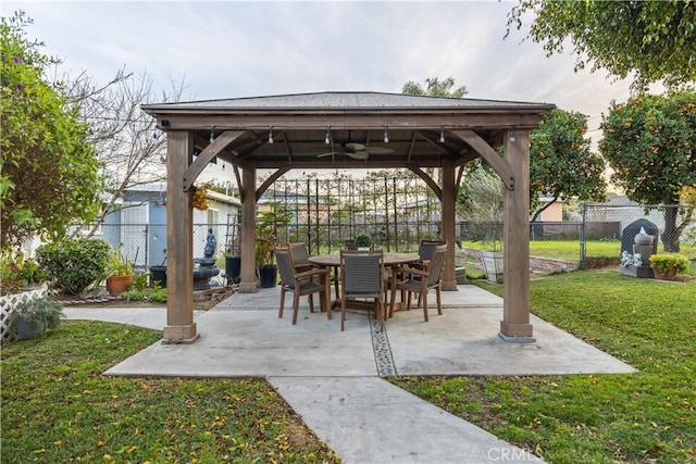 view of patio / terrace featuring a gazebo, outdoor dining space, fence, and a ceiling fan