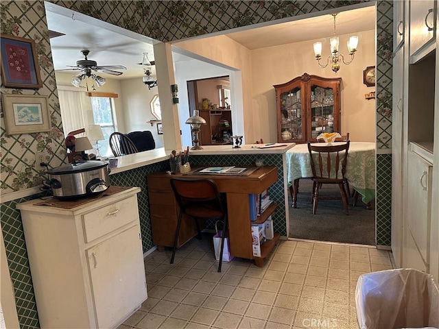 kitchen featuring light tile patterned floors, ceiling fan with notable chandelier, wainscoting, and wallpapered walls