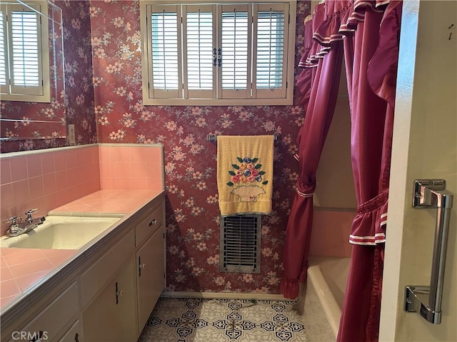 full bathroom with tile patterned floors, shower / tub combo, wallpapered walls, baseboards, and vanity