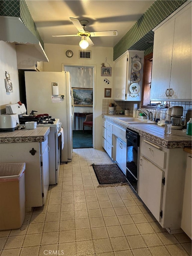 kitchen featuring visible vents, white range with gas stovetop, a sink, black dishwasher, and white cabinetry