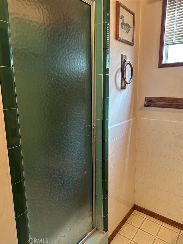 bathroom with a stall shower and tile walls