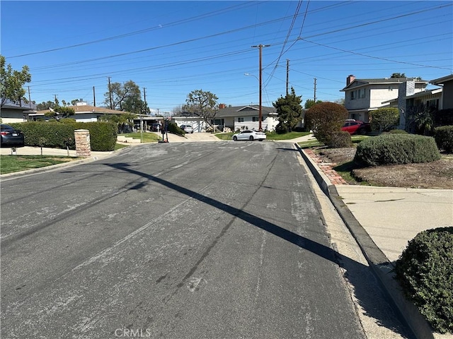 view of street with a residential view, curbs, and street lighting